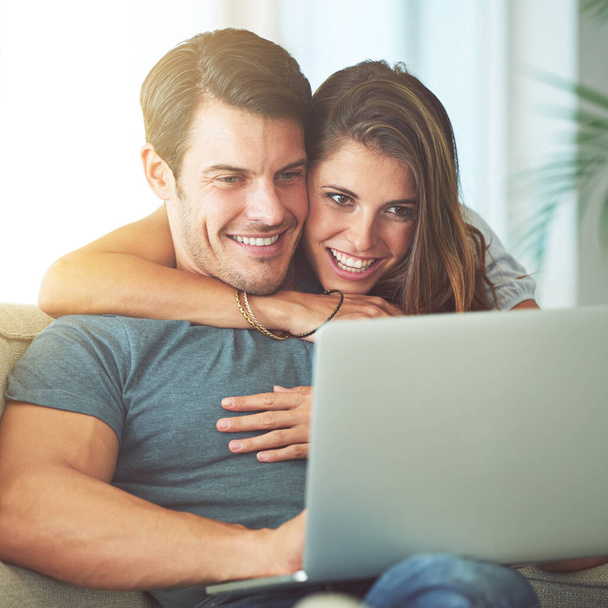 Watching movies is their idea of a perfect weekend. an affectionate young couple using a laptop at home - Foto, afbeelding