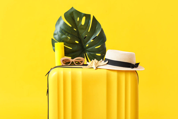 Walizka z akcesoriami plażowymi i liściem palmy na żółtym tle - Zdjęcie, obraz