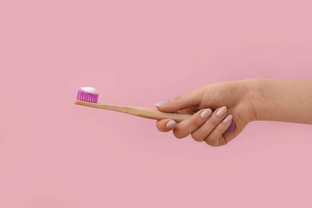 Female hand with toothbrush and paste on pink background - Foto, Bild