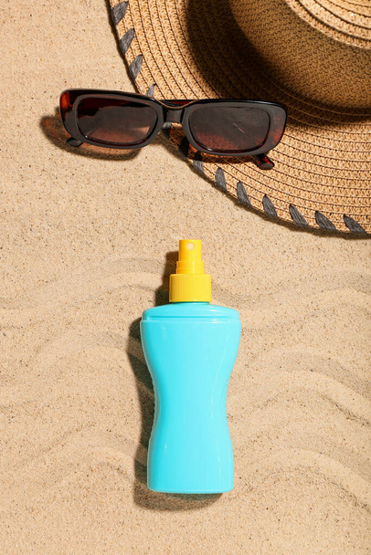Composición creativa con crema protectora solar y accesorios de playa sobre arena - Foto, imagen