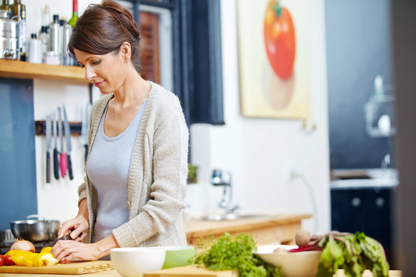 Gutes Essen aus frischen Zutaten zubereiten. eine attraktive Frau, die Gemüse an der Küchentheke hackt - Foto, Bild