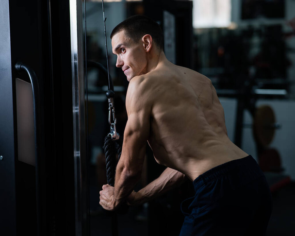 Shirtless man doing triceps pulldown at the gym - Foto, afbeelding