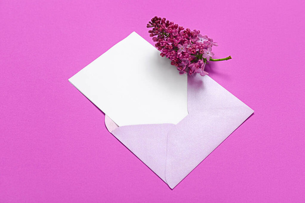 Envelope with blank card and beautiful lilac on purple background - Фото, зображення
