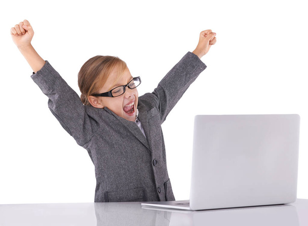 Ze heeft een mooie toekomst. Een klein meisje in drukke kledij zit achter een laptop een overwinning te vieren - Foto, afbeelding