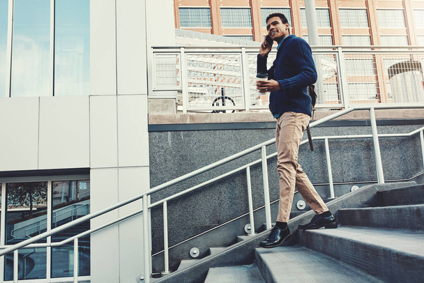 Blijven bewegen is zijn mantra voor succes. een jonge zakenman met behulp van een mobiele telefoon tijdens het lopen door de stad - Foto, afbeelding