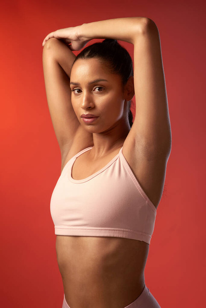 Wake up, workout and win that glow. Studio portrait of a sporty young woman stretching her arms against a red background - Photo, Image