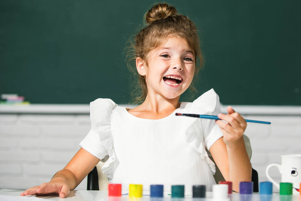 Little girls drawing a colorful pictures with pencil crayons in school classroom. Painting kids. Funny kids emotions - Foto, afbeelding