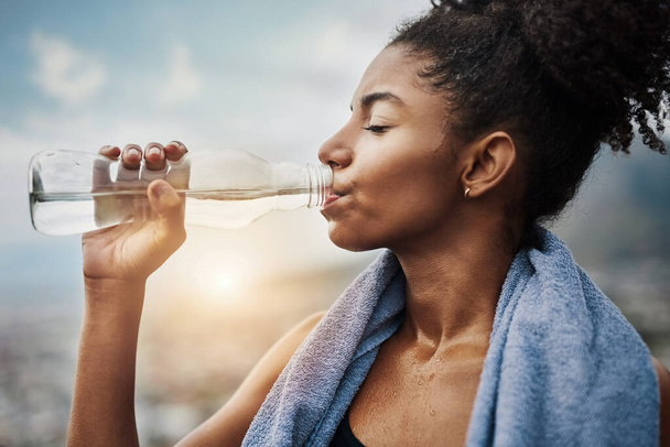 Заправка после утомительной тренировки. Спортивная молодая женщина пьет воду во время тренировок на открытом воздухе - Фото, изображение
