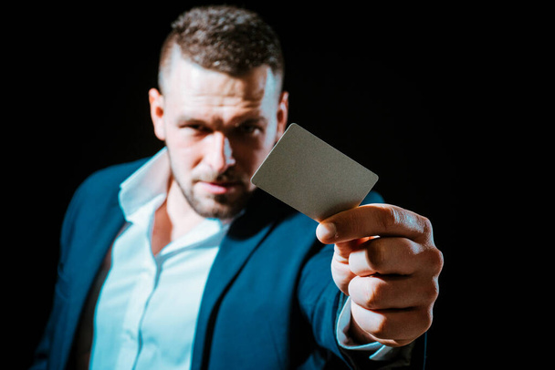 Young man giving his credit card looking at the camera, black background. Business man paying with a credit or debit card Businessman with a creditcard - Foto, Imagem