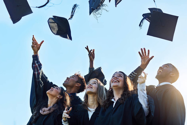 C'est officiel. un groupe d'étudiants jetant leurs chapeaux dans les airs le jour de la remise des diplômes - Photo, image