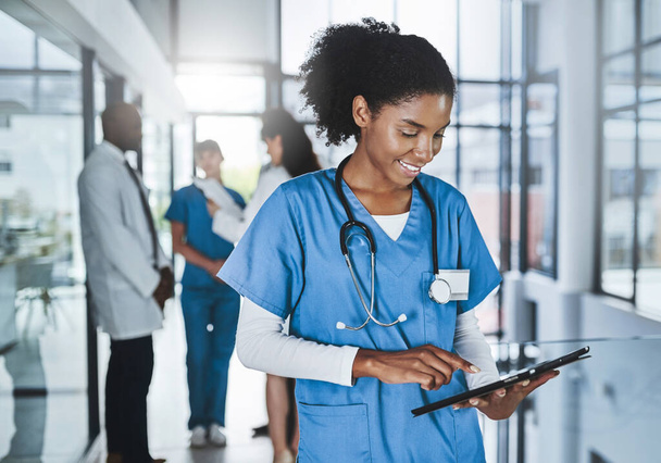 Making medical research smarter with smart tech. a young doctor using a digital tablet in a hospital with her colleagues in the background - Photo, image