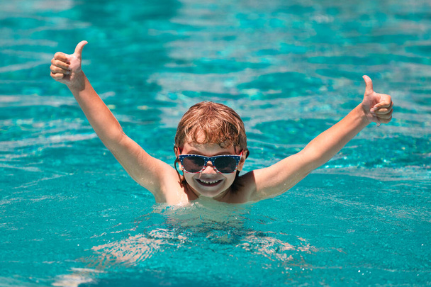 Excited child in sunglasses in pool in summer day. Kid in swimming pool - Photo, Image