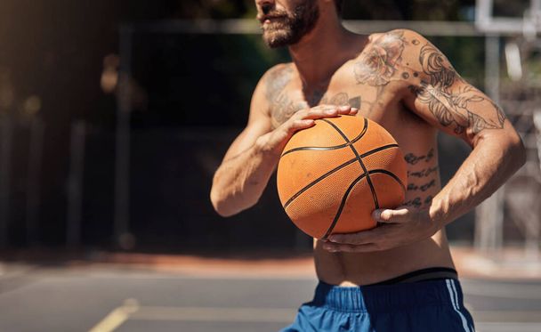 Een slanke, gemene ballin-machine worden. Close-up shot van een sportieve man met een basketbal op een sportveld - Foto, afbeelding