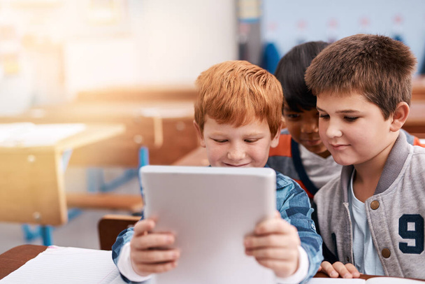 Wow, e 'meglio di un libro. due bambini delle elementari che navigano su un tablet digitale all'interno della classe durante il giorno - Foto, immagini