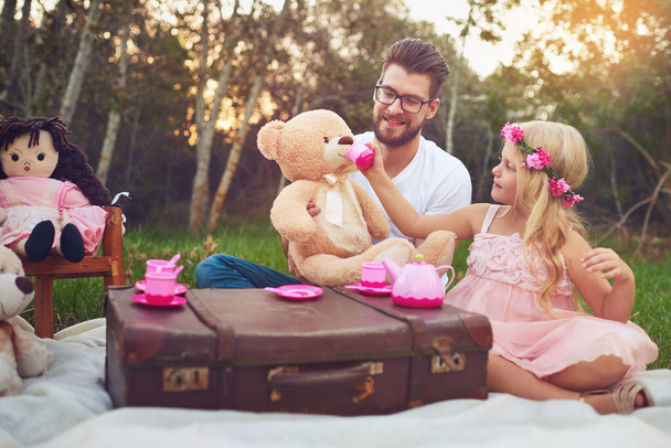 M. Beans doit aussi essayer mon thé. une fille et un père joyeux faisant une partie de thé avec un tas de jouets en peluche au milieu d'un jardin - Photo, image