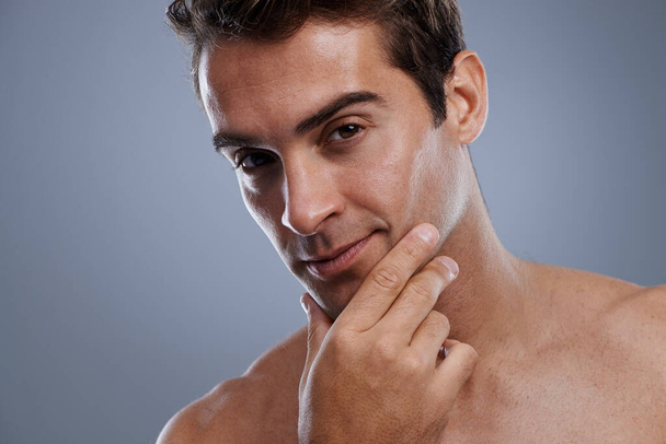 Even men like to be soft....Studio shot of a handsome young man applying cream to his face - Foto, Imagen