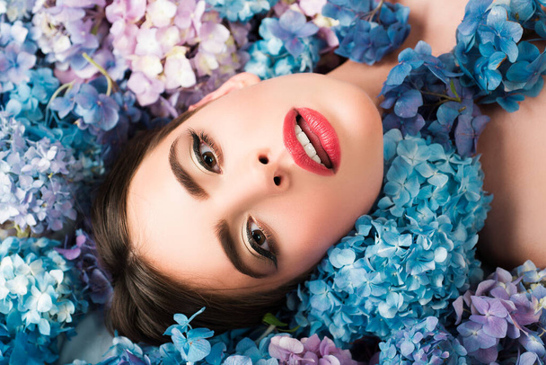 Woman beauty. Girl lying on flowers. Unity with nature. Blossom. Makeup cosmetics and skincare - Fotoğraf, Görsel