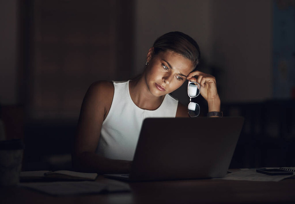 A stressz a végső szenvedélygyilkos. egy fiatal üzletasszony, aki kimerültnek tűnik, miközben laptopot használ késő este a munkahelyén. - Fotó, kép