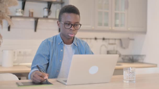Giovane uomo africano che lavora su computer portatile e tablet grafico, Progettazione - Filmati, video
