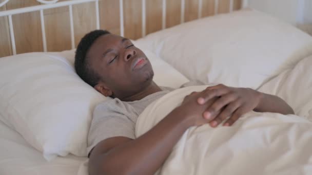 Genç Afrikalı adam uyanıyor ve yataktan ayrılıyor. - Video, Çekim