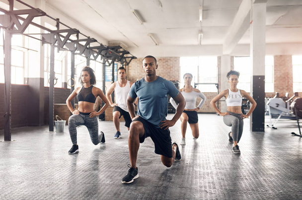 Haz esos movimientos para conseguir esos músculos. un grupo de jóvenes haciendo saltos juntos durante su entrenamiento en un gimnasio - Foto, Imagen
