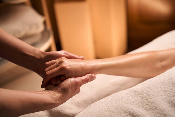 Foto recortada de massagista alongamento polegar e dedo mindinho do cliente feminino - Foto, Imagem