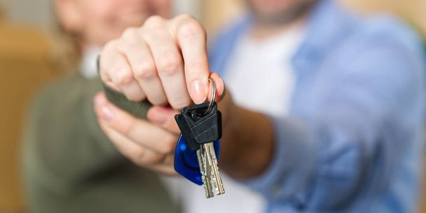 Couple showing keys to new apartment. real estate mortgage, loan concept. moving in new house. Young smiling couple holding their new house keys. first own apartment or house. - Foto, immagini
