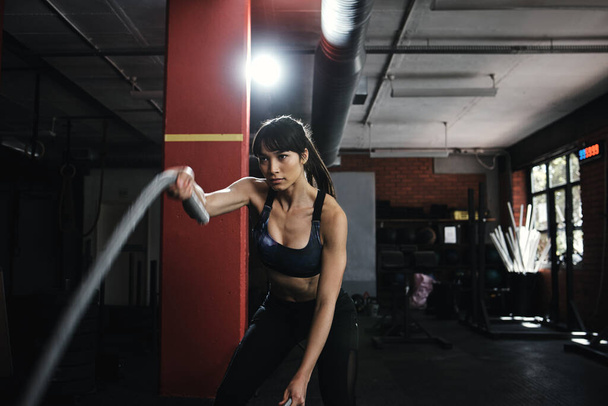 Én mozgatom az életem szálait. Egy fiatal nő nehéz kötélkiképzést tart az edzőteremben. - Fotó, kép
