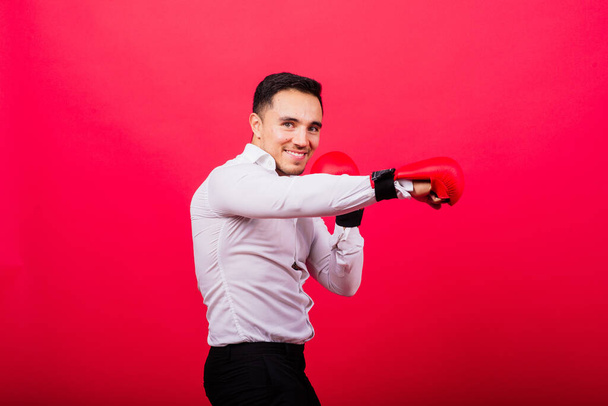 Handsome young businessman with a boxing gloves. Studio red background - Fotoğraf, Görsel