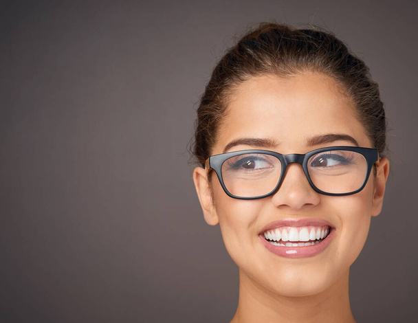 Theres beauty all around. Studio shot of a beautiful young woman wearing glasses against a gray background - Photo, Image