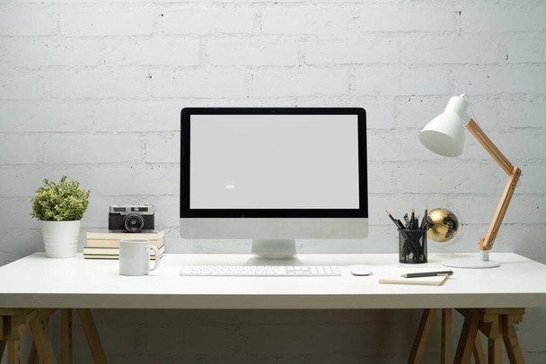 Creative workspace with blank computer desktop, lamp, camera and potted plat. Business presentation, banner website. - Photo, Image