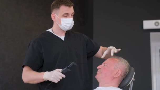 Retrato de médico cirurgião fazendo marcas no rosto masculino, homem idoso. Vídeo 4k de alta qualidade - Filmagem, Vídeo
