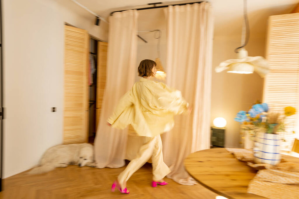 スタイリッシュなスタジオアパートメントのインテリアでベージュ色のトーンとともに動きのあるぼやけた女性の姿歩く - 写真・画像