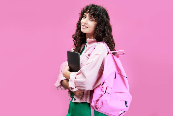 Chytrá studentka vysoké školy nebo střední školy v džínové bundě stojící před kamerou na růžovém pozadí - Fotografie, Obrázek