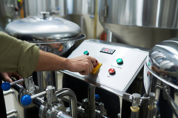 Imagen de primer plano del trabajador que lanza el equipo cervecero para la fermentación y maduración de la cerveza - Foto, Imagen