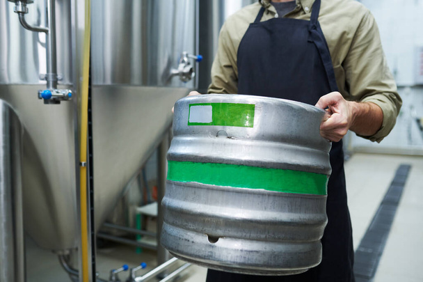 Microbrewery worker carrying heavy keg with beer, small business concept - Foto, Imagen