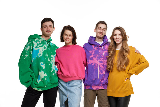 Portrait of four young people, friends in colorful hoodies posing over white background. LGBTQIA supporters. Happiness. Concept of lgbt community, support, love, human rights, pride month - Photo, Image
