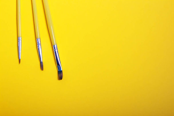 A set of paint brushes of different sizes on a yellow background. - Фото, изображение