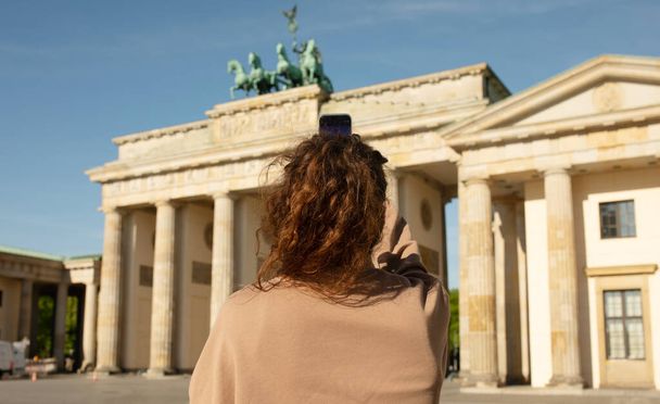 Tourist visiting Brandenburg Gate and taking photos with smartphone in Berlin, Germany   - Photo, Image