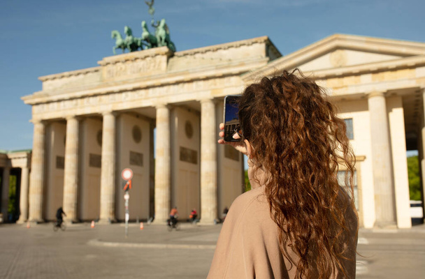 Tourist visiting Brandenburg Gate and taking photos with smartphone in Berlin, Germany   - Fotografie, Obrázek