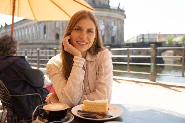 Beautiful woman eating dessert and drink coffee at outdoors cafe - Foto, imagen