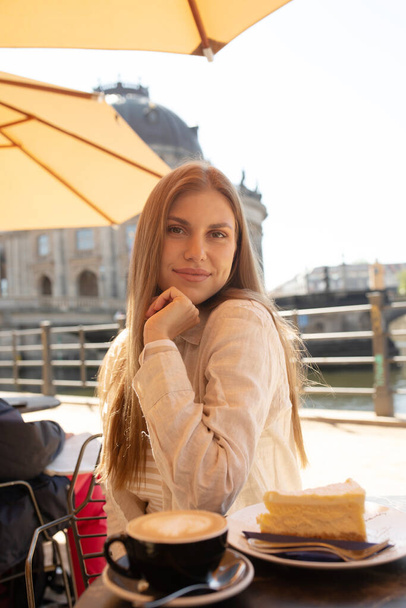 Beautiful woman eating dessert and drink coffee at outdoors cafe - Zdjęcie, obraz