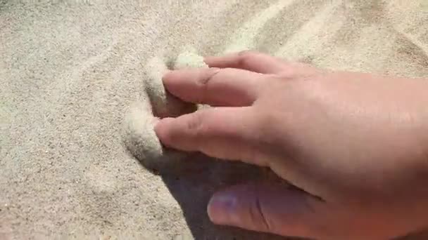 Kobieca ręka machająca na piasku w letni słoneczny dzień. Piasek przez palce dłoni. POV. Pojęcie morza, plaży, wakacje, wakacje, relaks, turystyka, podróże, dotyk, przyjemność, odpoczynek, relaks - Materiał filmowy, wideo