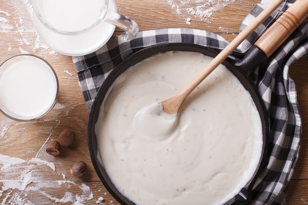 bechamel sauce in a pan and milk on the table top view - Foto, Imagen