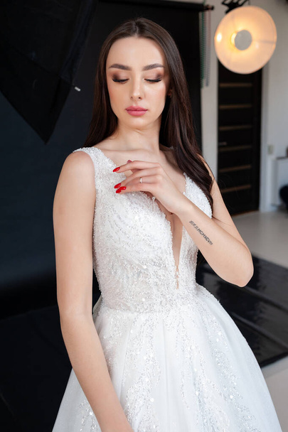 belle mariée brune en robe blanche posant en studio - Photo, image