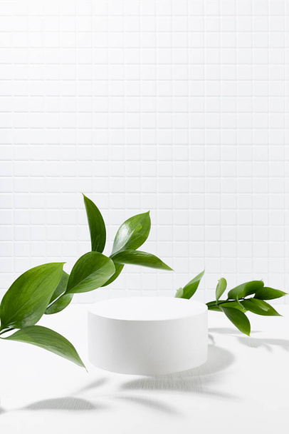 Summer abstract white stage, one round podium mockup for presentation cosmetic products, goods, advertising, in interior, tiny mosaic tile, fresh tropical green leaves in sunbeam, shadow, vertical. - Foto, immagini
