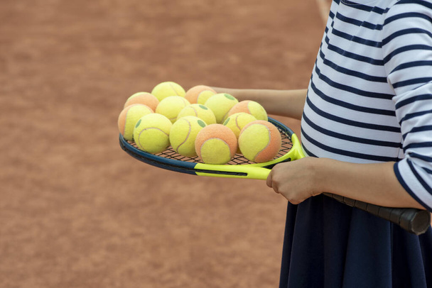 Lasten tennistä. Mailaa, jalkoja ja palloa. Kesäaktiviteetteja lapsille tenniskerhossa. Rajattu kuva urheilu pikkutyttö tenniskentällä. Urheilullinen lapsi tyttö osuu tennispallo kanssa rako - Valokuva, kuva