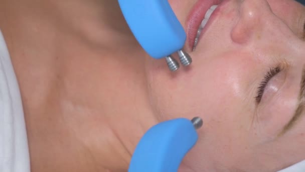 Facial skin rejuvenation using microcurrent therapy in a modern cosmetology clinic. Hardware cosmetology. Care of a womans face in a beauty salon - Footage, Video