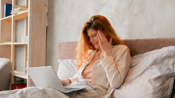 Freelancer Kaukasialainen sairas nainen työskentelee kauko kotiin sänky paha tunne päänsärky. III opiskelija tyttö opiskelee kaukana kannettavan makuuhuoneessa kärsivät kivulias päänsärky migreeni väsynyt tietokone - Valokuva, kuva