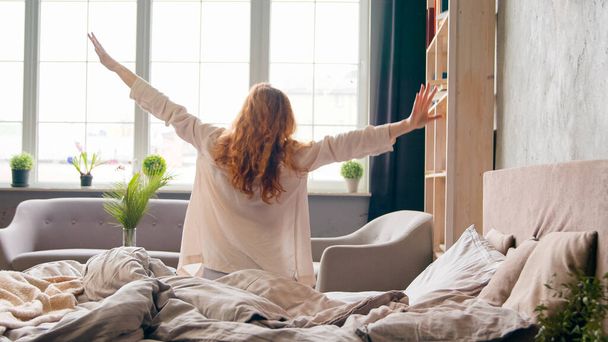 Kaukasische Frau, die morgens im gemütlichen Bett auf weichen orthopädischen Matratzen aufwacht, beginnt den neuen Tag. Mädchen wach im Hotelschlafzimmer aufstehen aus gesundem Schlaf Stretching Körper Schlaflosigkeit Erholung - Foto, Bild